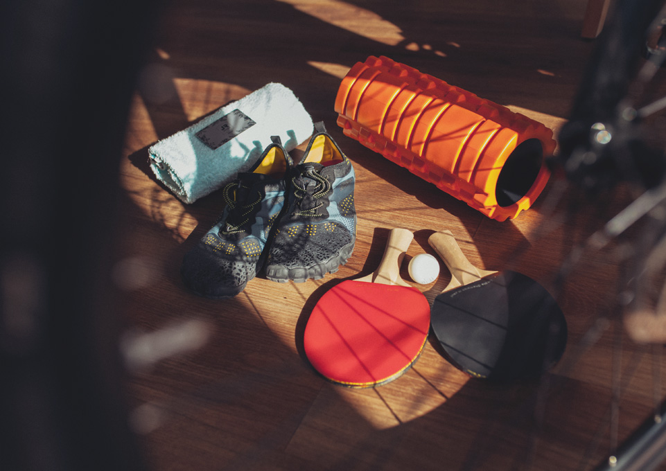 Sportausrüstung mit Laufschuhen, Handtuch, Faszienrolle und Tischtennisschlägern.