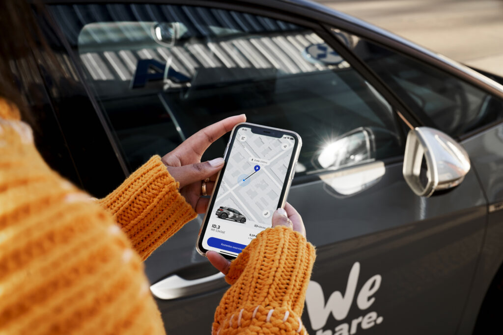 Mockup der WeShare App in Hand vor Auto